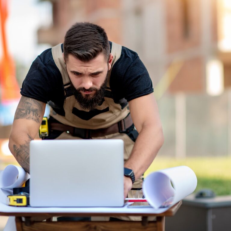 A builder on the job site works on his project planning using his laptop